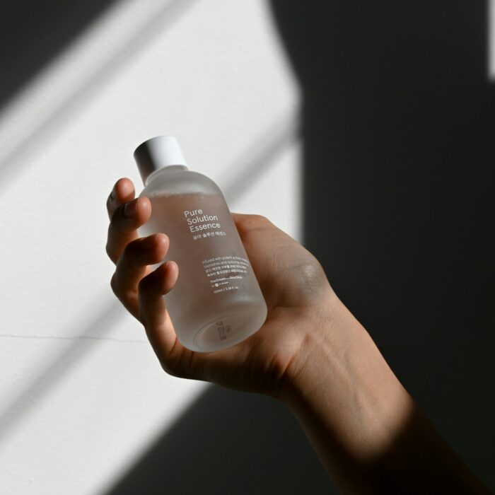 Hand holding a skincare bottle in raking light